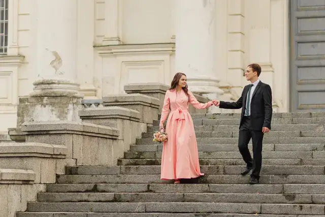 On the steps of an old architectural building, a beautiful wedding couple can be seen