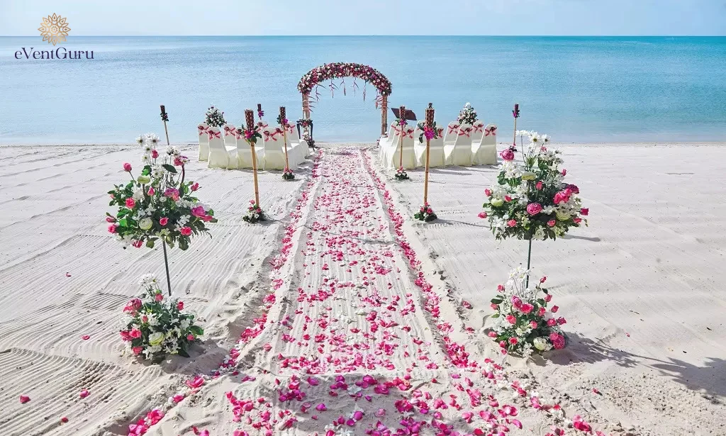 A beach wedding venue decorated with rose petals in red and pink