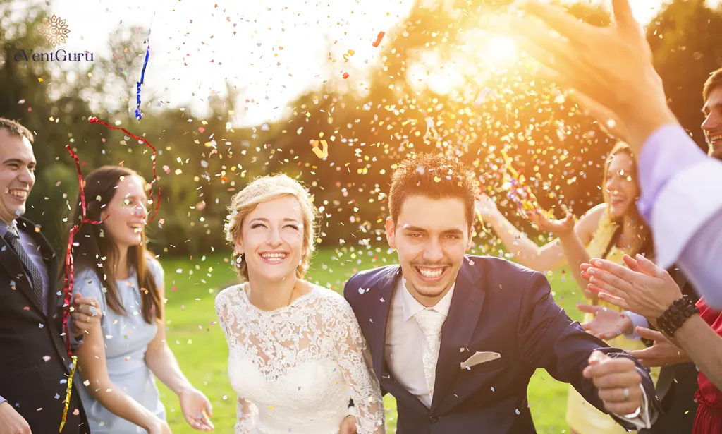 During the wedding party at a green and sunny park, newlyweds and their friends are showered with confetti.