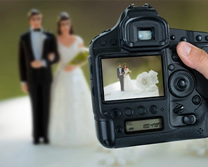 photographer holding camera for capture couple statue on cake