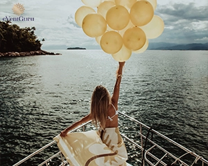 A woman standing on a yacht holding golden balloons